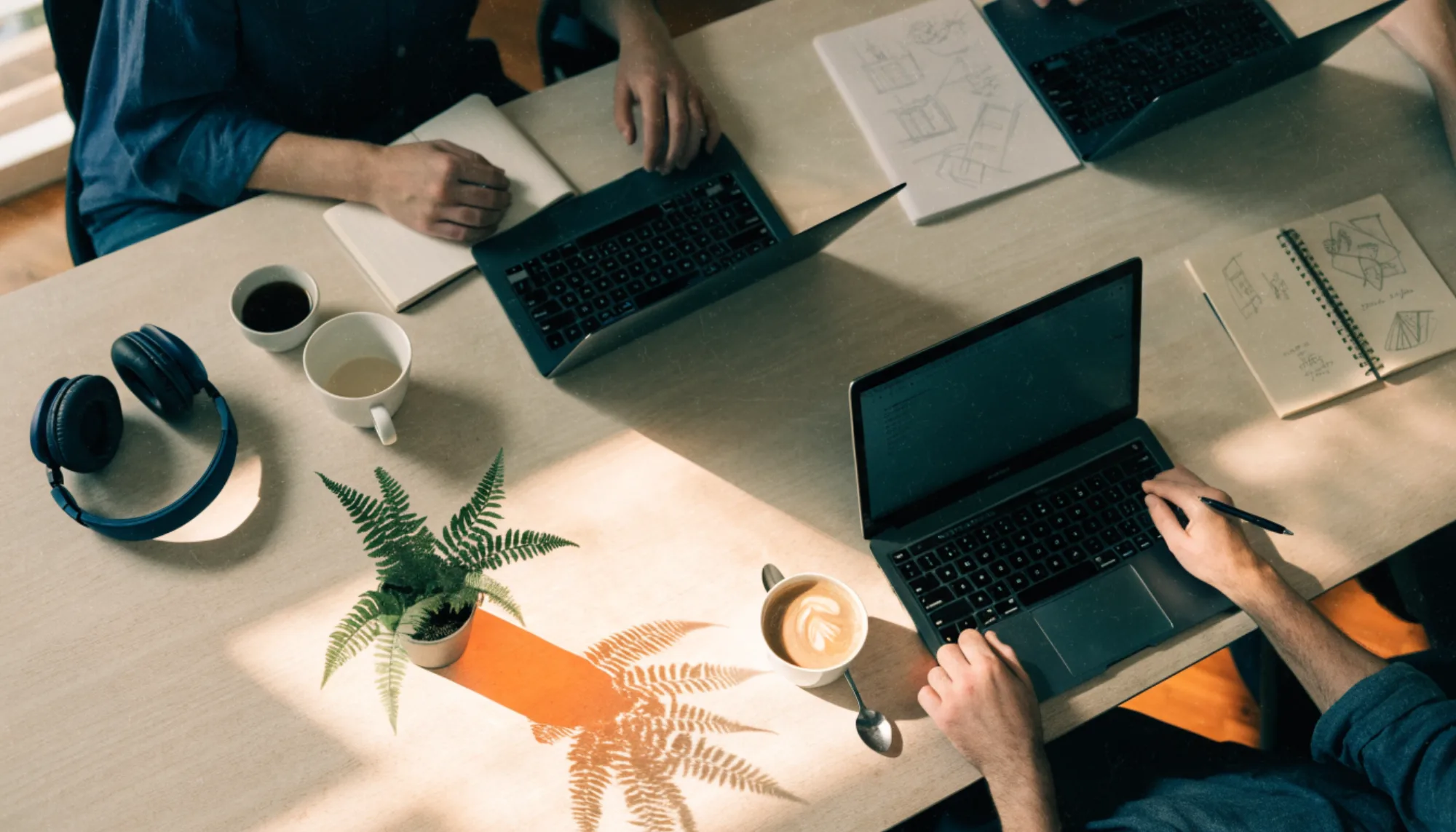 Laptops, notebooks and headphones on a shared table